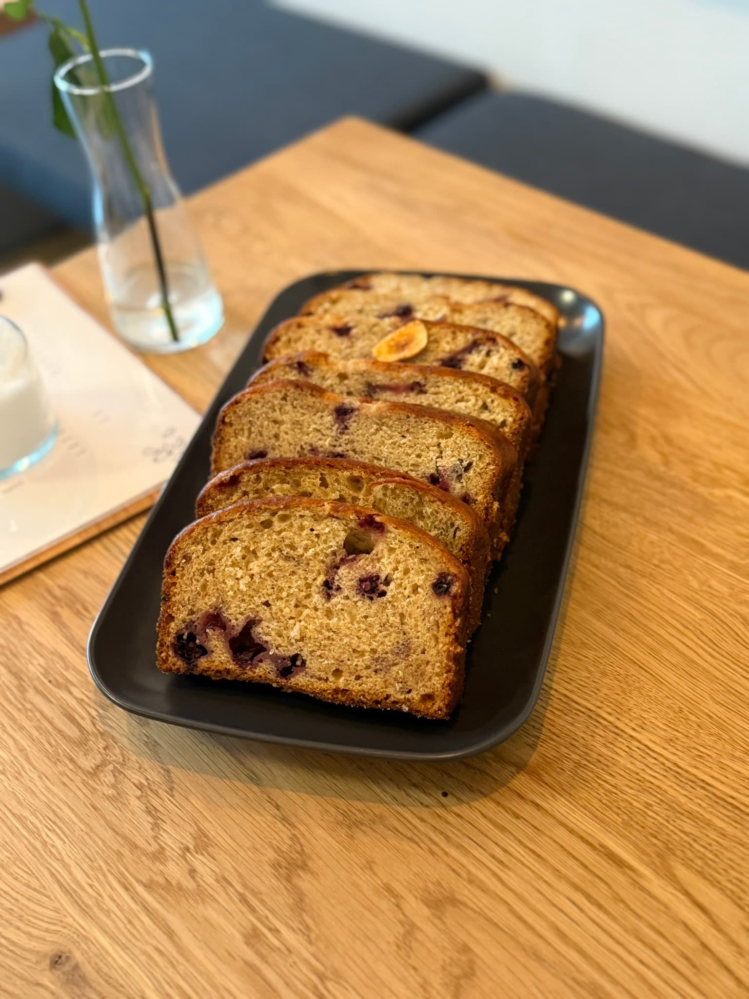 Bananenbrot mit Blaubeeren von de Bananas in Scheiben auf schwarzer Schale