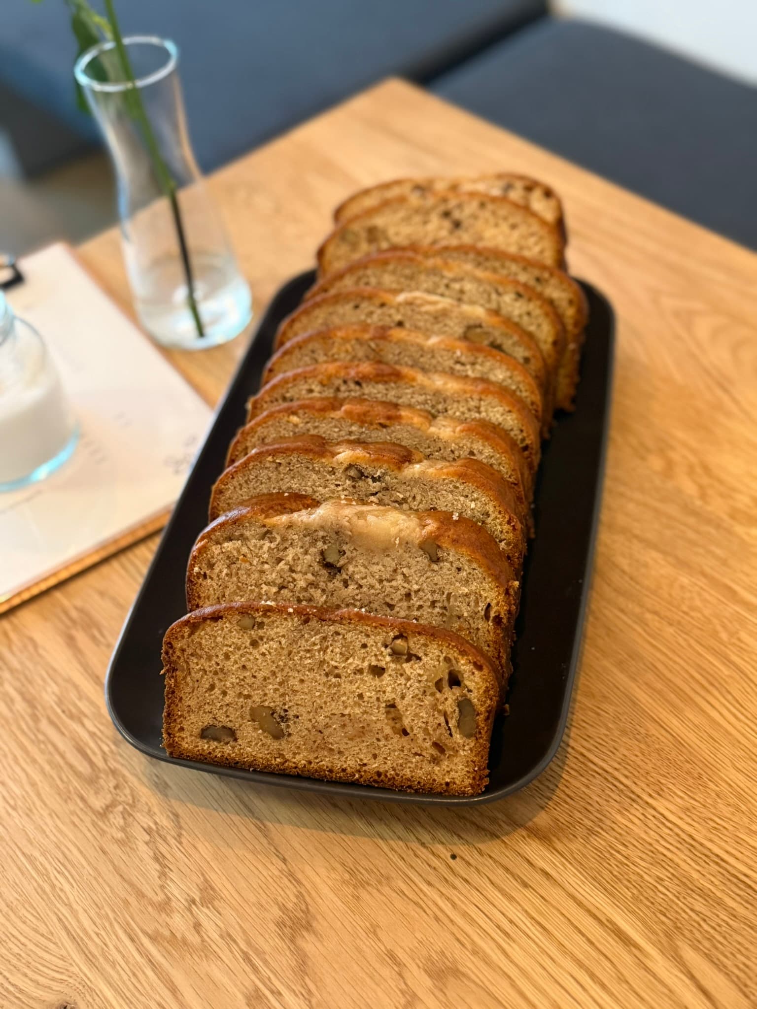 Bananenbrot mit Nüssen von de Bananas in Scheiben auf schwarzer Schale