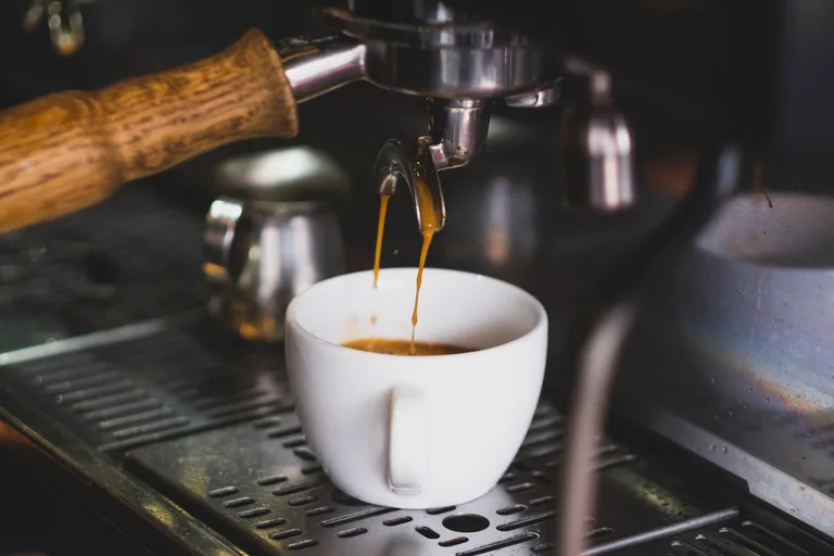 Espresso läuft aus Siebträger in weiße Tasse