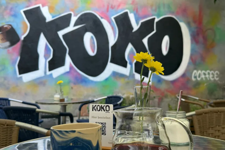 KOKO Coffee Lab Outdoor-Terrasse mit Keramiktasse und Pour-Over-Karaffe, Graffiti-Wand und Sonnenschirm